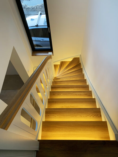 U-shaped staircase with railing, LED strips lighting the steps.