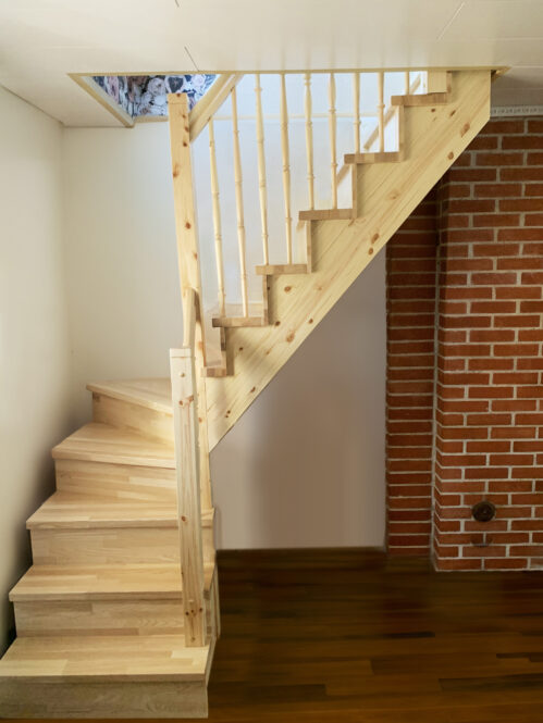 Pine wood staircase with light finish. L-shaped staircase.