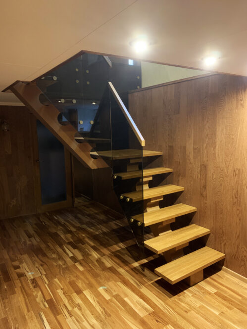 L-shaped staircase with glass railings with a central beam.