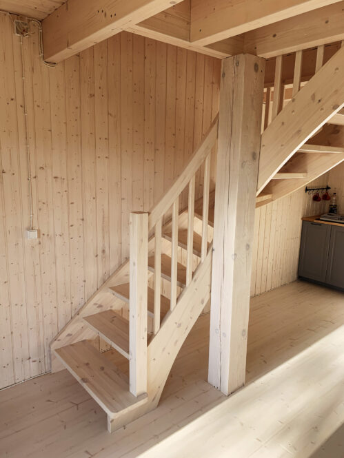 L-shaped pine staircase with light finish.