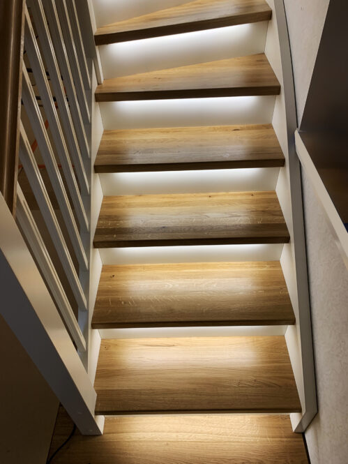 Staircase with classic stringers and oak steps. LED lighting.