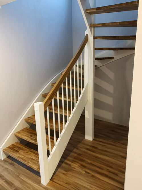 U-shaped staircase with oak steps and light finish.