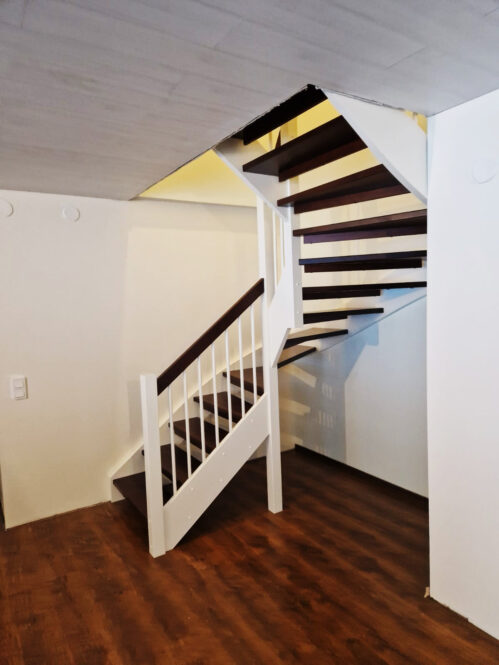 U-shaped staircase with a central beam and glass railing. Oak steps.