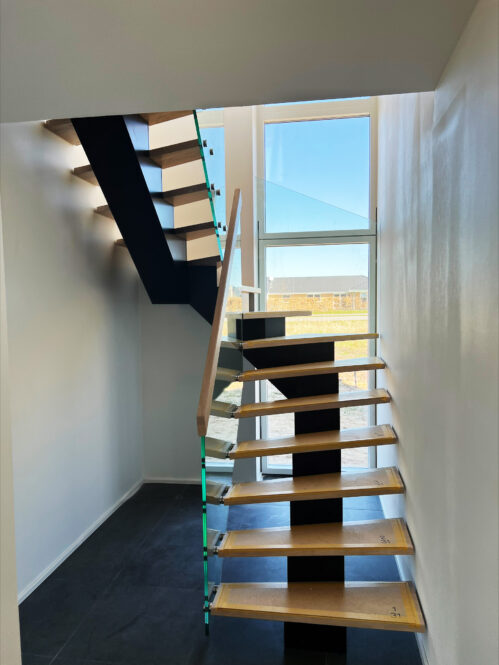 U-shaped staircase with a central beam and glass railing. Oak steps.