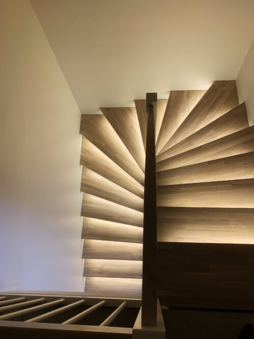 U-shaped wooden staircase with light finish and LED lighting.