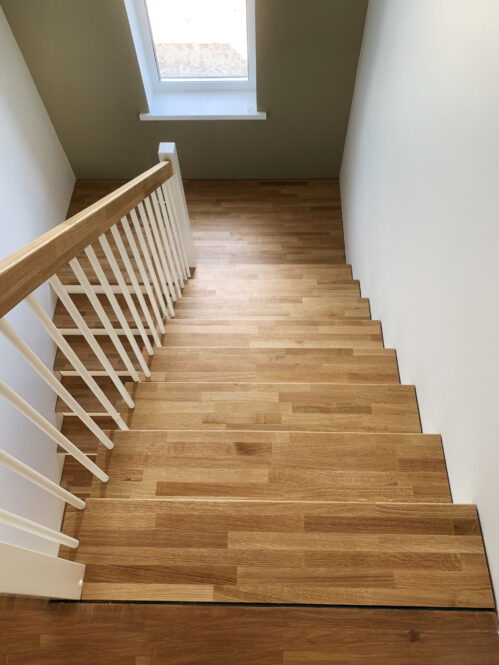 U-shaped staircase with modern stringers and light finish.