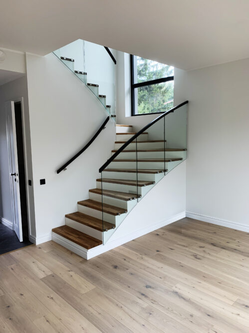 U-shaped designer staircase with glass railing and oak steps.