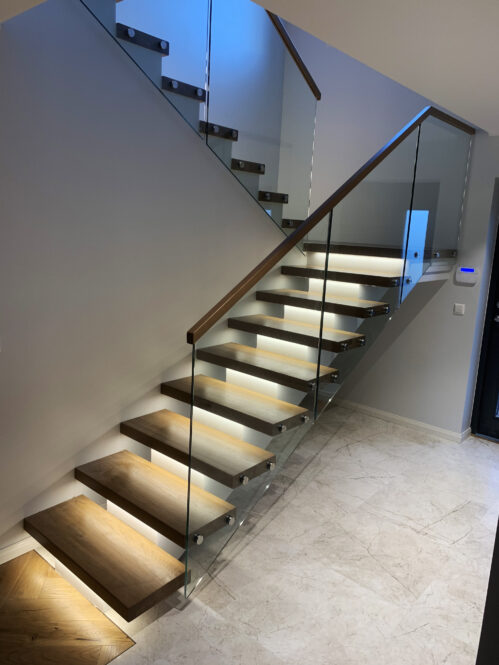 U-shaped staircase with oak steps and central beam. The staircase has LED lighting.