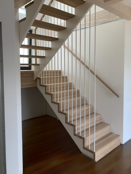 U-shaped designer staircase with oak steps and light finish.